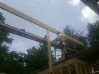 Carpenter setting a ridge beam over a new addition frame — Ice Dam Removal by Roofing Brothers in Yoncalla