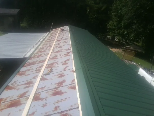 Old rusted panels beside newly installed green metal roofing — Wind Damage Roof Repair by Roofing Brothers in Yoncalla