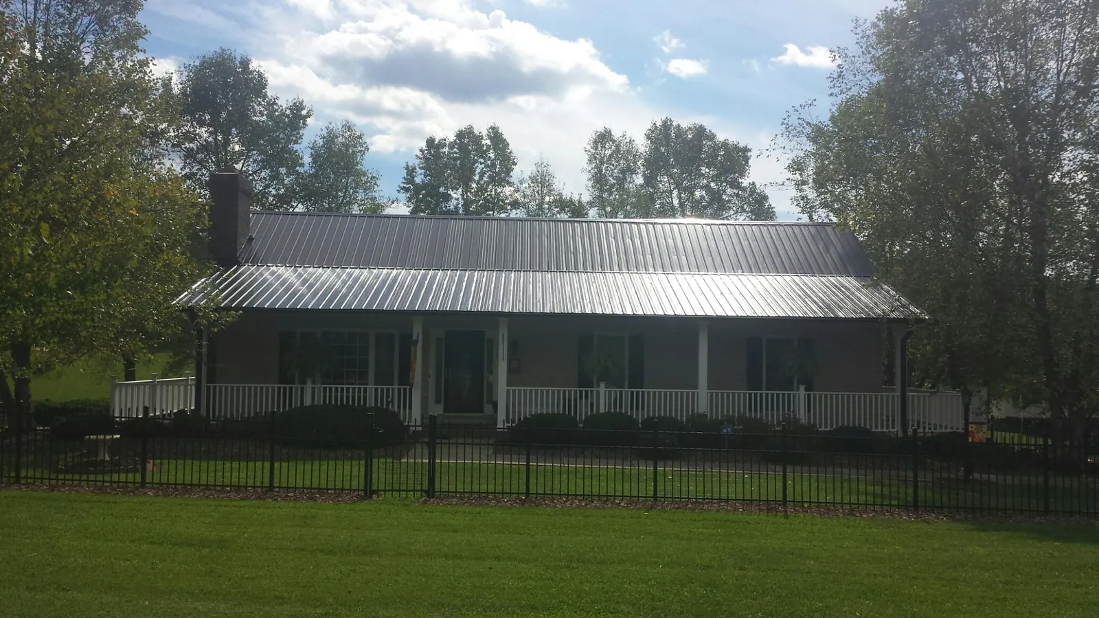 Gray metal roof on a brick ranch with a full width front porch — Gutter Guard Installation work by our crew in Yoncalla