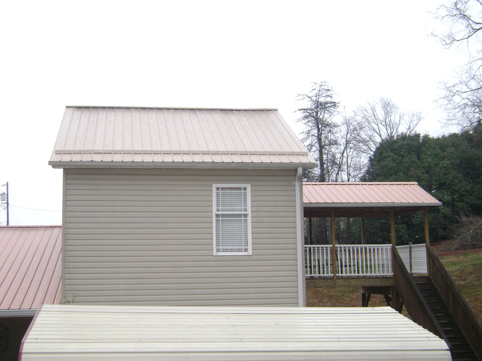 Tan metal roofs on a two story addition and attached porch, from a Roof Replacement job in Yoncalla